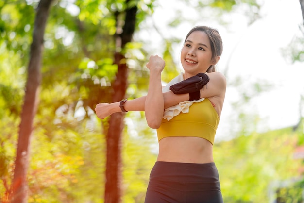 Giovane adulto asiatico allegro Attraente e forte stretching mattutino prima di correre nel parco Concetto di sport Stile di vita sano Giovane corridore di fitness donna che si allunga prima di correre sul parco
