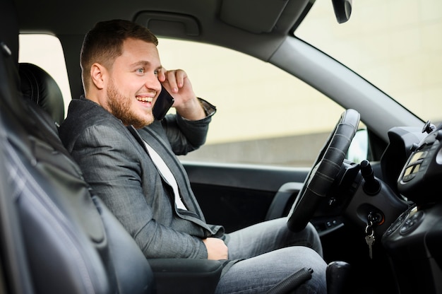 Giovane al volante con il suo telefono sul suo orecchio