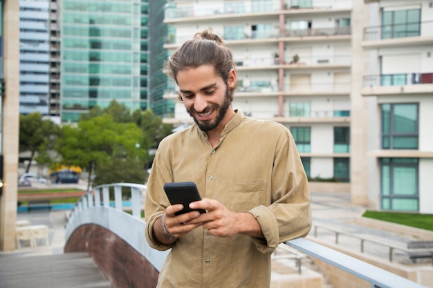 Giovane allegro che per mezzo dello smartphone