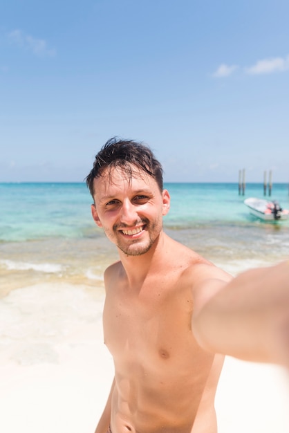 Giovane allegro che prende selfie alla spiaggia