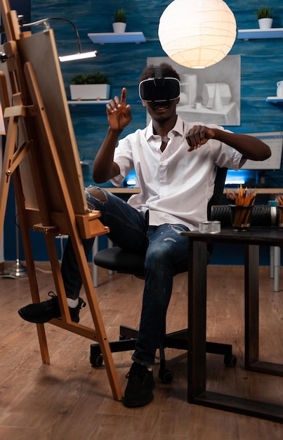 Giovane artista che indossa l'auricolare per realtà virtuale immaginando di disegnare uno schizzo che lavora al progetto della scuola di pittura nell'atelier d'arte. Studente che disegna un vaso su tela che disegna ombre per il suo capolavoro creativo