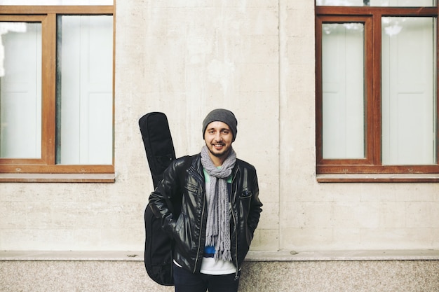 Giovane artista di strada attraente con la sua chitarra