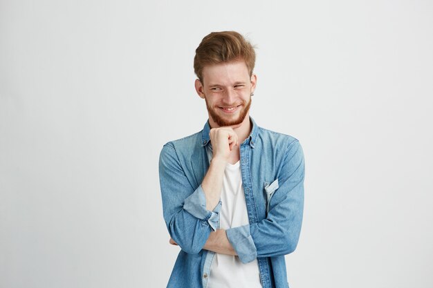 Giovane astuto astuto che pensa esaminando lato con la mano sul mento.