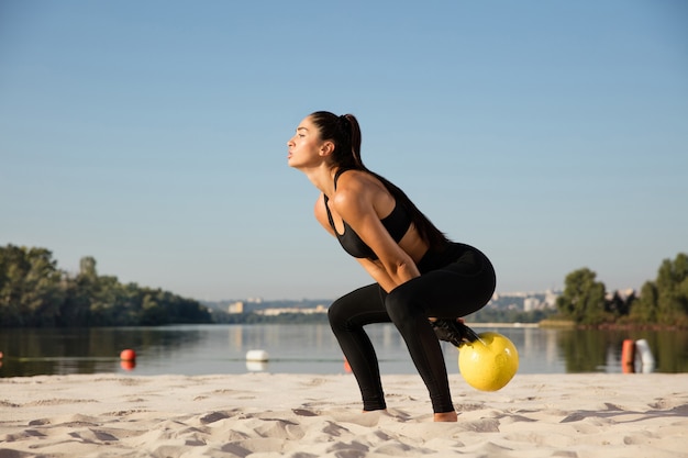 Giovane atleta femminile in buona salute facendo allenamento in spiaggia