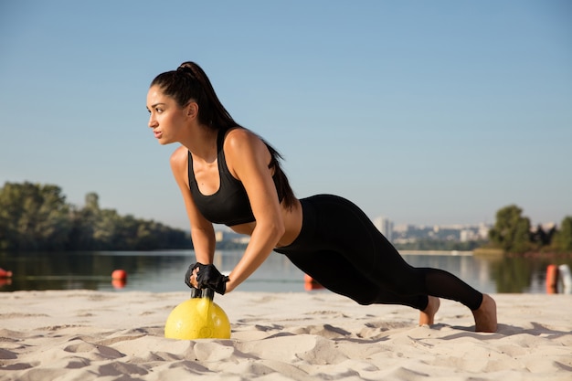 Giovane atleta femminile in buona salute facendo allenamento in spiaggia