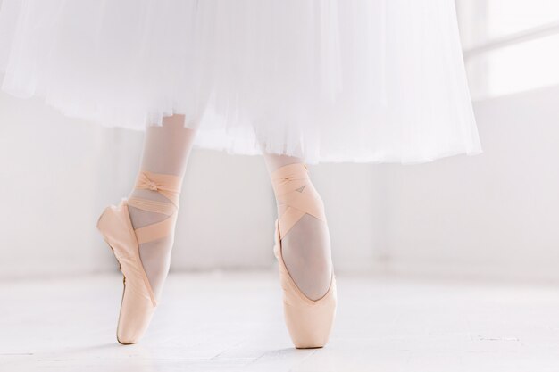 Giovane ballerina, primo piano su gambe e scarpe, in piedi in posizione di punta.