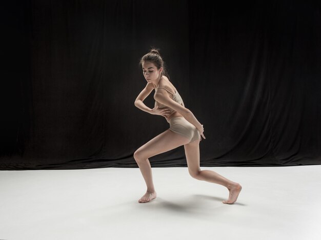 Giovane ballerino teenager che balla sul fondo bianco dello studio del pavimento. Progetto ballerina.