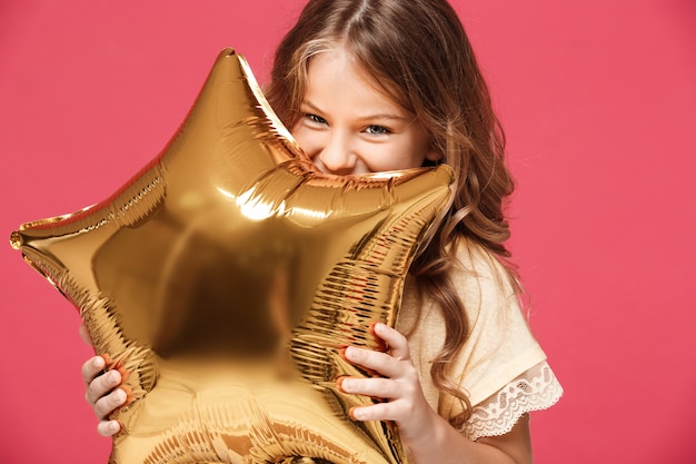 Giovane baloon grazioso della tenuta della ragazza e sorridere sopra la parete rosa