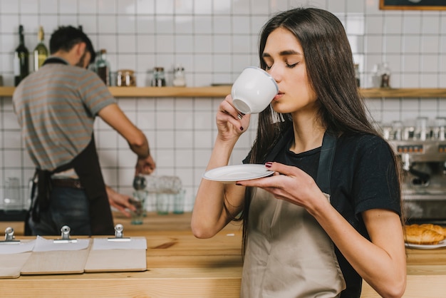 Giovane barista che beve bevanda calda