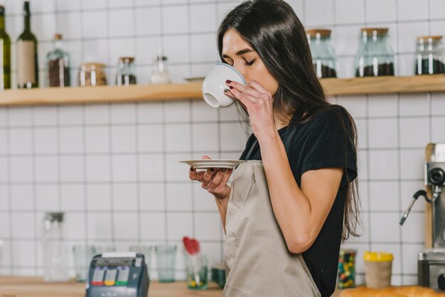 Giovane barista che beve bevanda calda