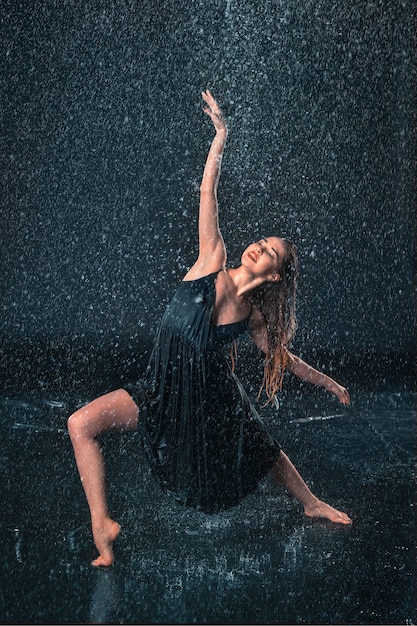 Giovane bella ballerina moderna danza sotto gocce d'acqua