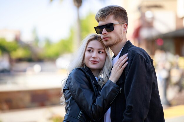 Giovane bella bionda che abbraccia il suo ragazzo e distoglie lo sguardo Foto di alta qualità