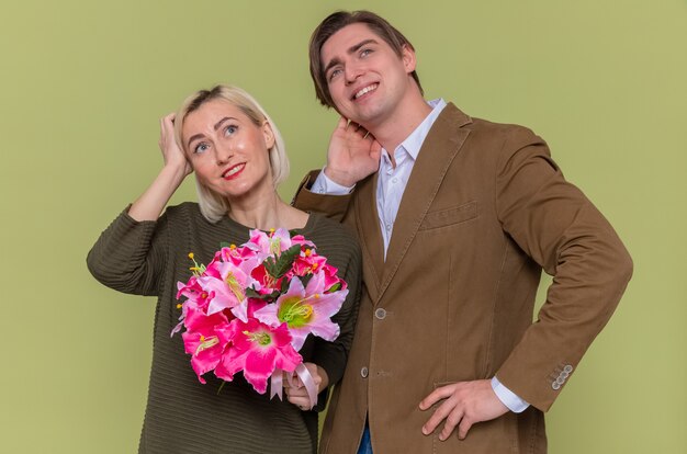 Giovane bella coppia felice uomo e donna con bouquet di fiori