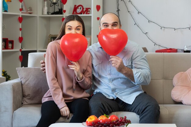 Giovane bella coppia felice uomo e donna con palloncini a forma di cuore sorridente