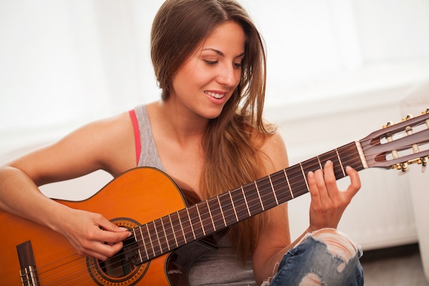 Giovane bella donna a suonare la chitarra