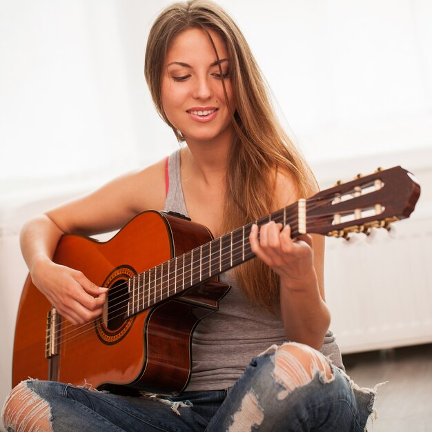 Giovane bella donna a suonare la chitarra