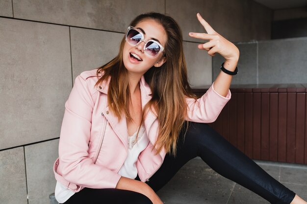 Giovane bella donna alla moda hipster in giacca di pelle rosa