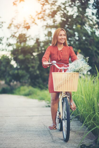 Giovane bella donna asiatica che guida una bicicletta in un parco