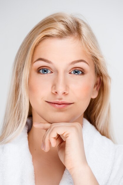 Giovane bella donna bionda nel sorridere dell'accappatoio