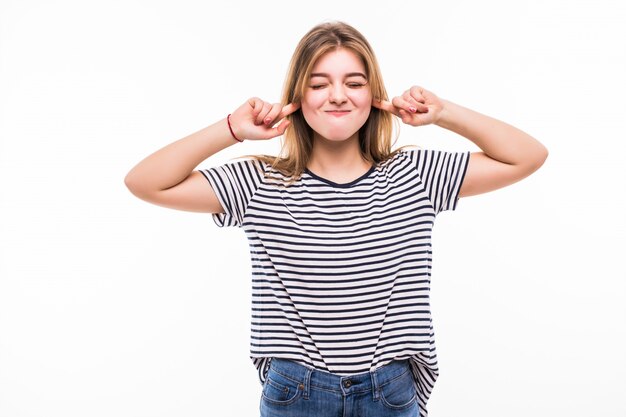 Giovane bella donna castana che porta vestito a strisce casuale sopra le orecchie bianche isolate del rivestimento murale con le dita con l'espressione infastidita