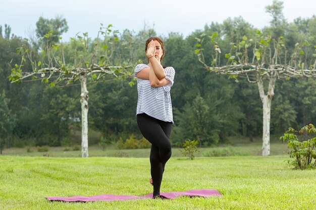 Giovane bella donna che fa esercizio di yoga all'aperto