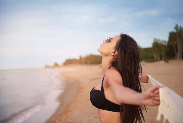 Giovane bella donna che ha divertimento sulla spiaggia