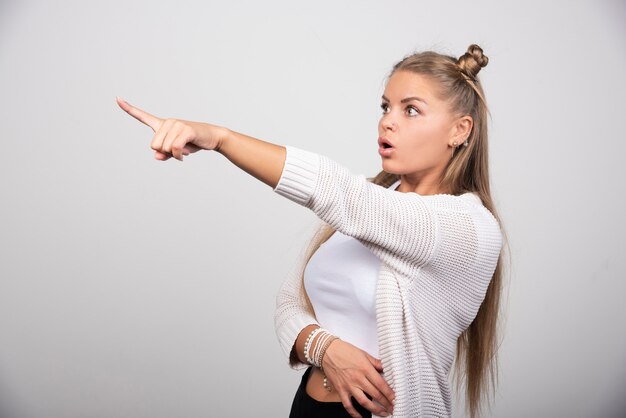 Giovane bella donna che indica con la mano e il dito di lato.