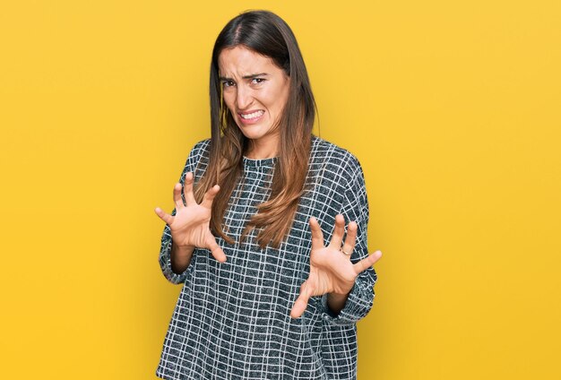 Giovane bella donna che indossa abiti casual espressione disgustata dispiaciuta e timorosa che fa il viso disgustato perché la reazione di avversione con le mani alzate