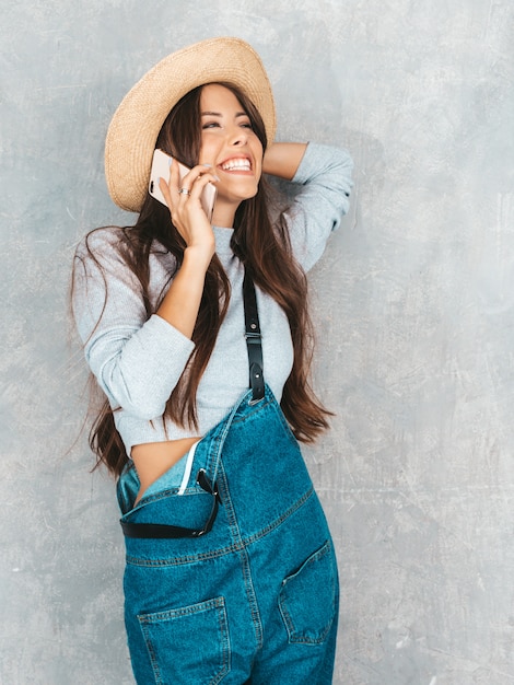 Giovane bella donna che parla sul telefono. Ragazza scioccata alla moda in abiti casual e cappello di tuta estiva.