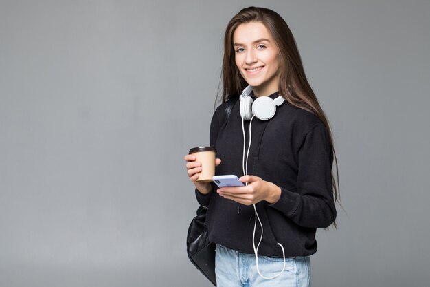 Giovane bella donna che per mezzo dello Smart Phone isolato sulla parete grigia