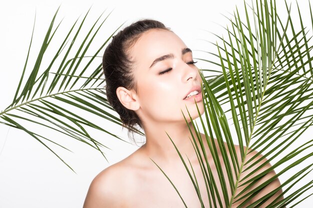 Giovane bella donna che posa con le foglie di palma verdi