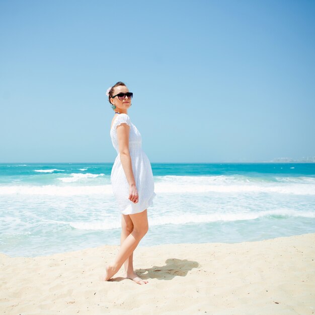 Giovane bella donna che posa sulla spiaggia