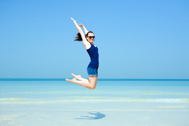 Giovane bella donna che posa sulla spiaggia