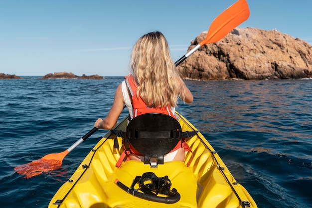 Giovane bella donna che viaggia in canoa