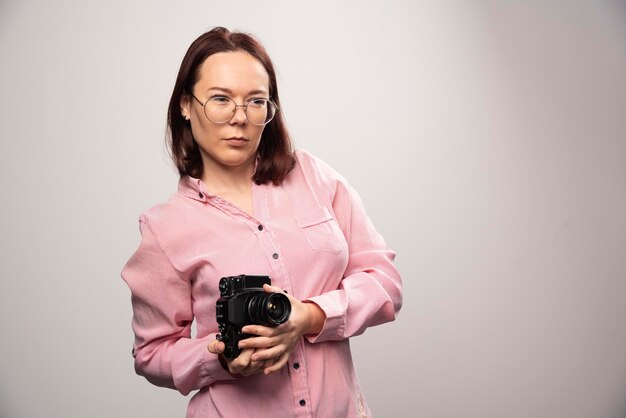 Giovane bella donna con una macchina fotografica su un bianco. Foto di alta qualità