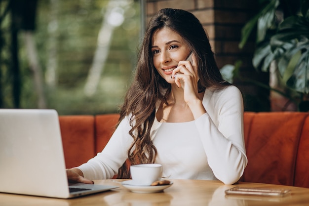 Giovane bella donna d'affari che lavora al computer in un caffè