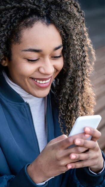 Giovane bella donna del ritratto che per mezzo del cellulare