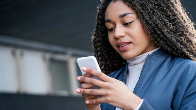 Giovane bella donna del ritratto che per mezzo del cellulare