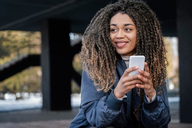 Giovane bella donna del ritratto che per mezzo del cellulare