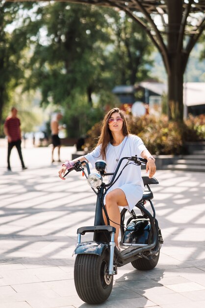 Giovane bella donna e un trasporto ecologico di scooter elettrico