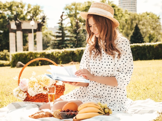 Giovane bella donna hipster in abito estivo alla moda e cappello. Donna spensierata che fa picnic all'esterno.