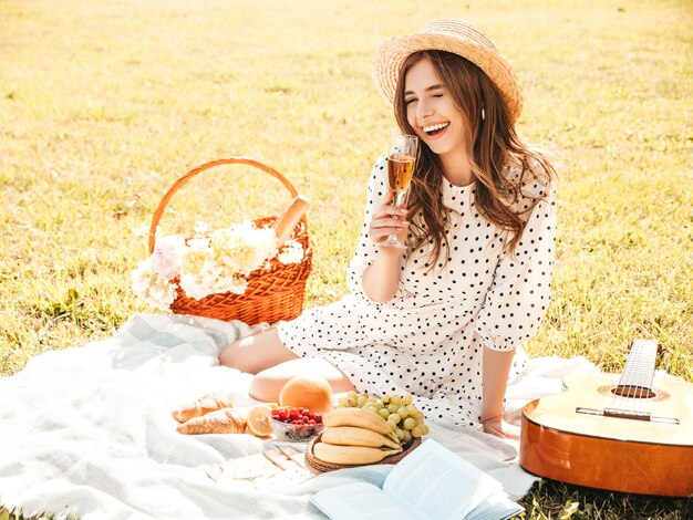 Giovane bella donna hipster in prendisole e cappello estivi alla moda. Donna spensierata che fa picnic all'esterno.