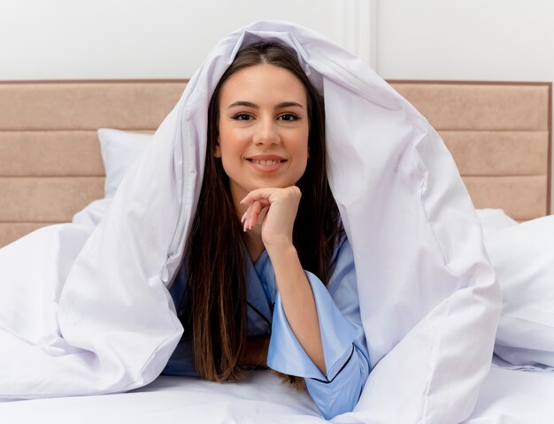 Giovane bella donna in pigiama blu che pone sul letto