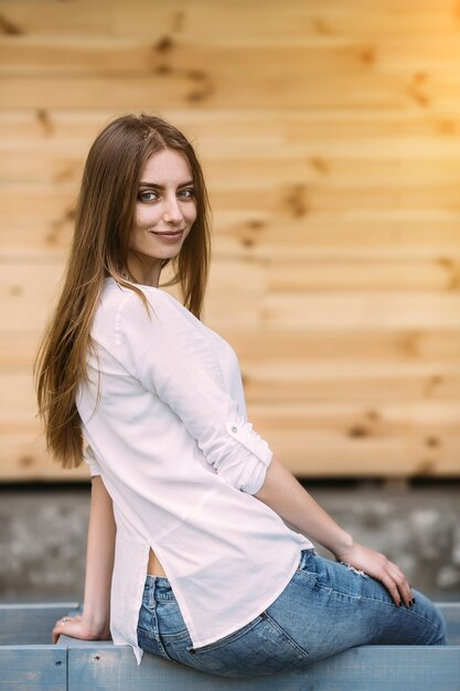 Giovane bella donna in posa contro un muro di legno
