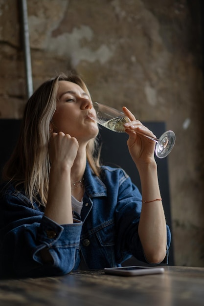 Giovane bella donna in un caffè, una donna che beve champagne in un caffè e parla.