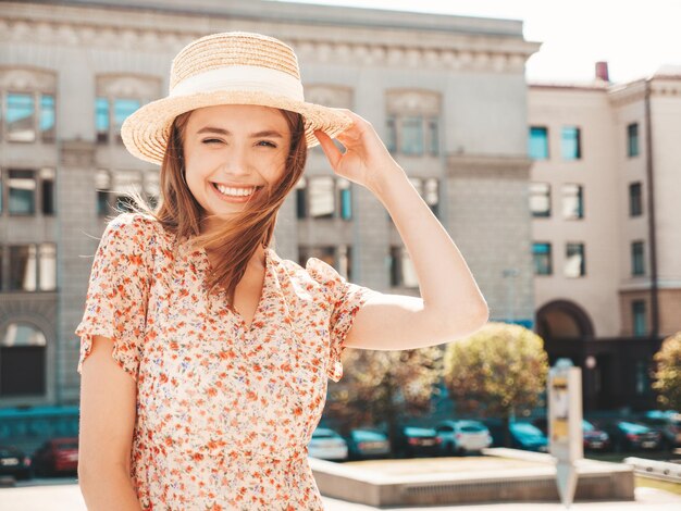 Giovane bella donna sorridente hipster in abito estivo alla moda Donna spensierata sexy in posa sullo sfondo della strada con cappello al tramonto Modello positivo che ride all'aperto Allegro e felice