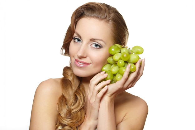 Giovane bella donna sorridente sexy che tiene un mazzo di uva in sue mani con capelli lunghi isolati su bianco