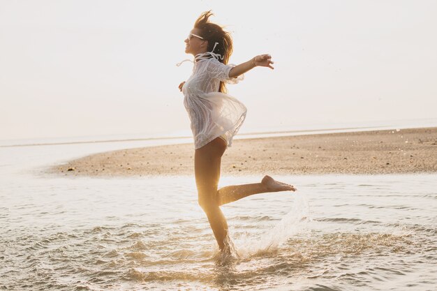 Giovane bella donna sottile sulla spiaggia al tramonto