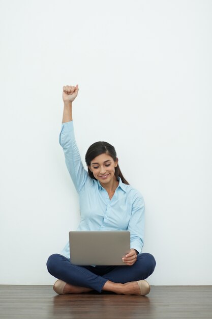 Giovane bella donna sul pavimento con il computer portatile