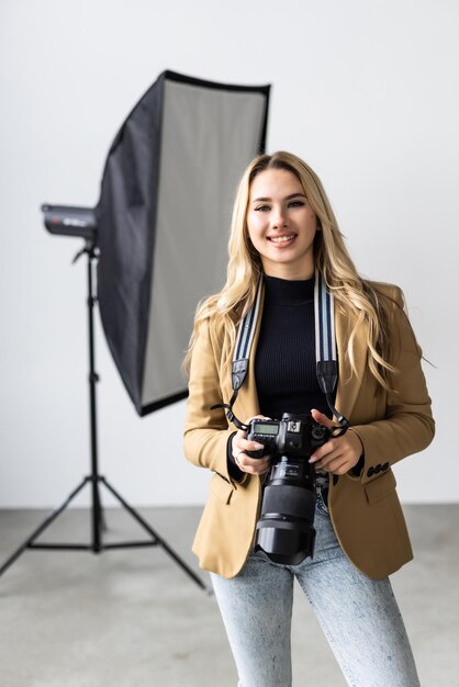 Giovane bella femmina in posa per un servizio fotografico in uno studio che un fotografo sta riprendendo con una fotocamera digitale